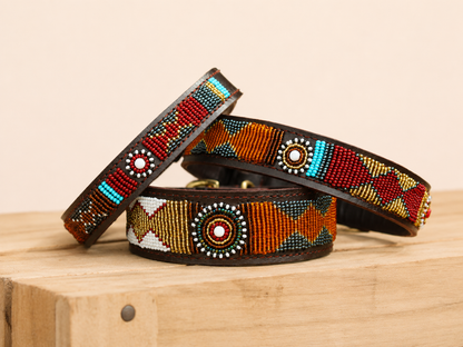 PAWNEE beaded leather dog collar with orange, red, turquoise and gold Maasai patterns on wooden crate